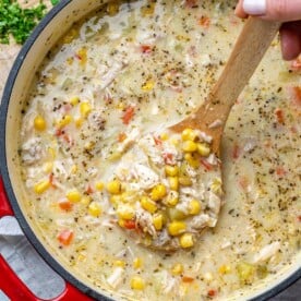 corn chowder soup with a hand holding a spoonful