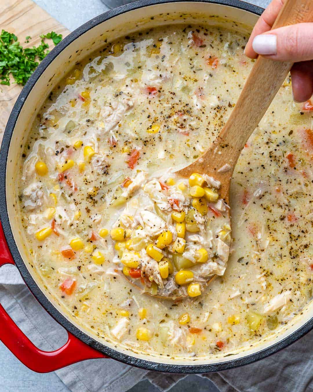 corn chowder soup with a hand holding a spoonful