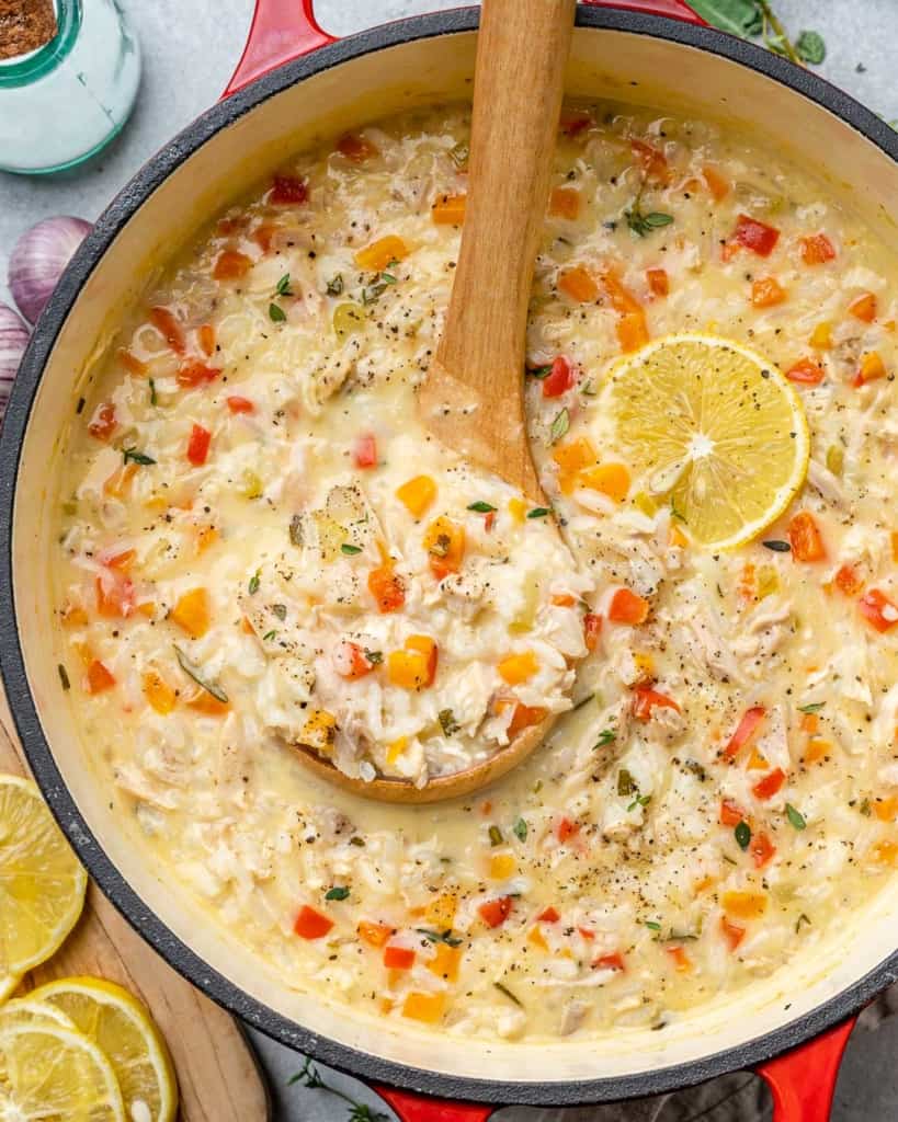 rice and turkey soup in a red pot with a spoonful of soup