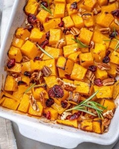 roasted butternut squash in a dish with pecans and dried cranberries.
