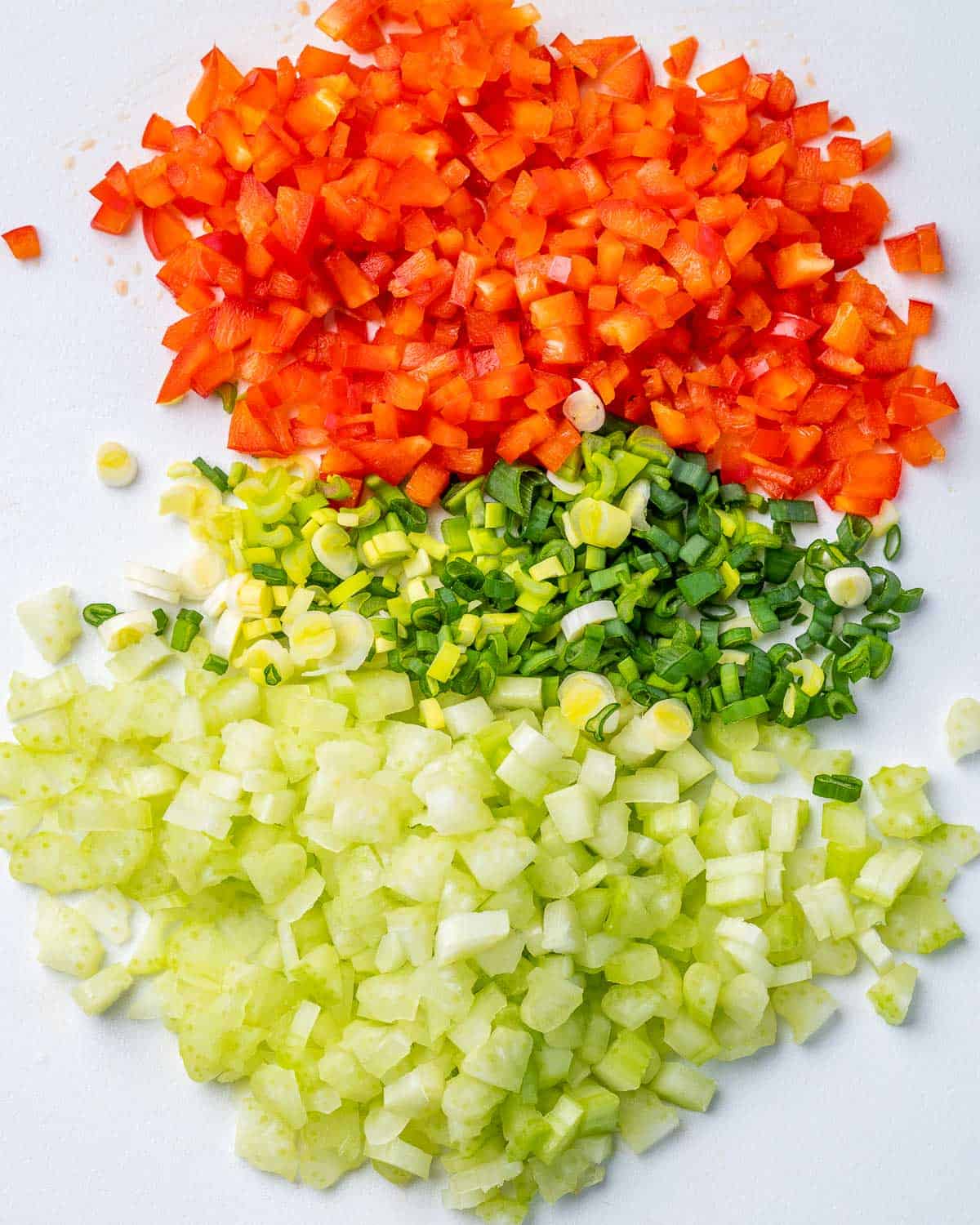 Diced celery, bell pepper, and green onions on cutting board.
