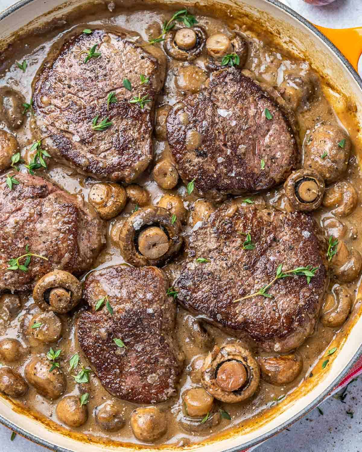 Top view of steaks and mushroom in a pan.