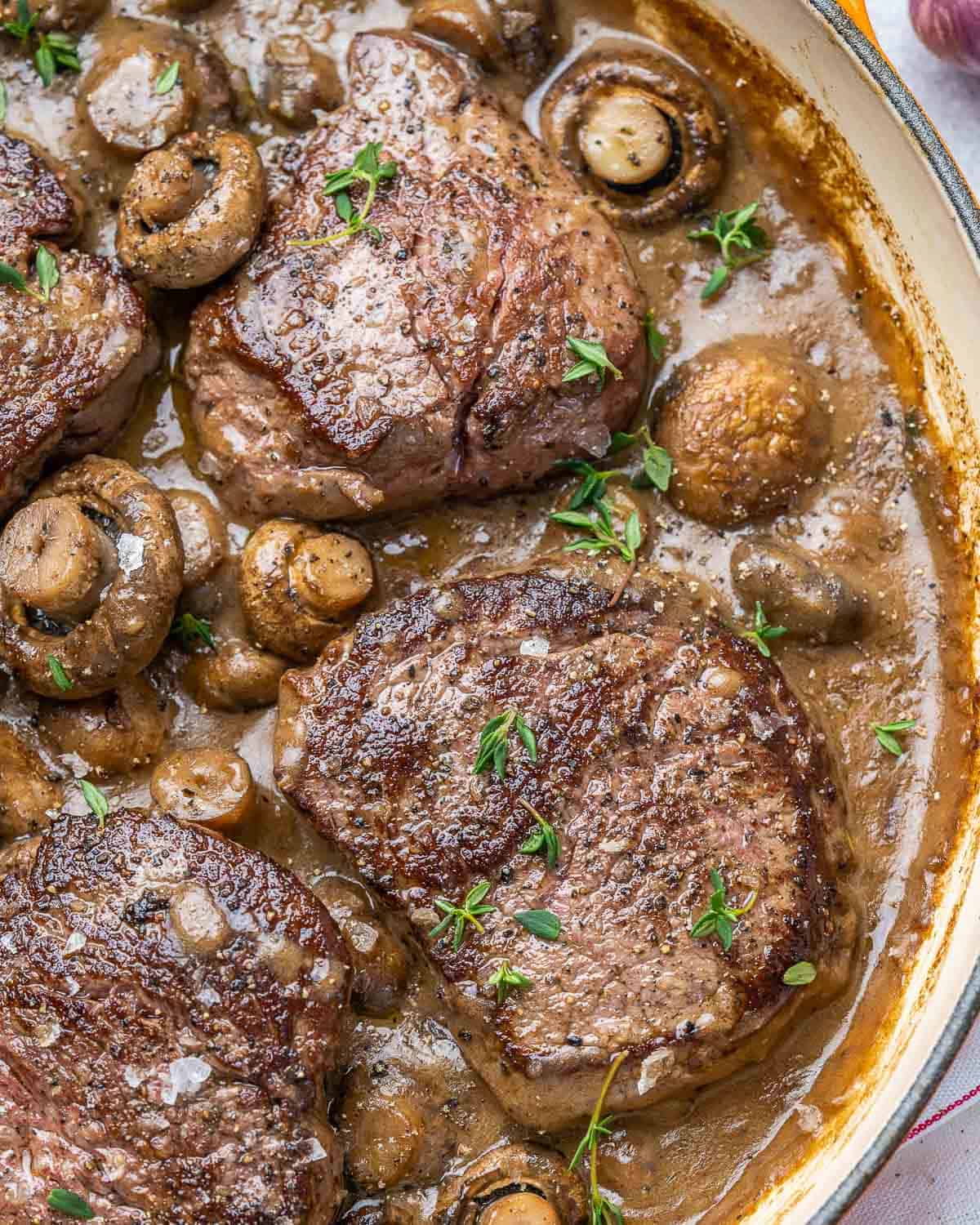 Filet steaks in pan with mushrooms and herbs. 
