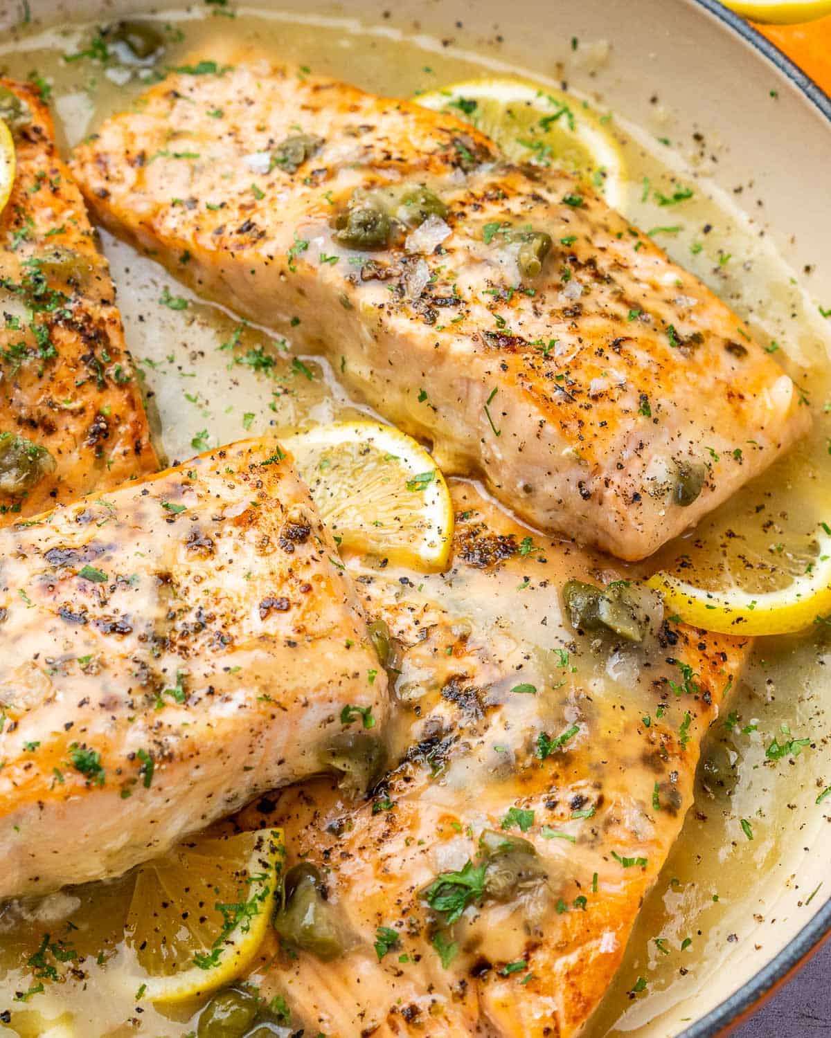 Close view of four salmon filets smothered in creamy lemon sauce.