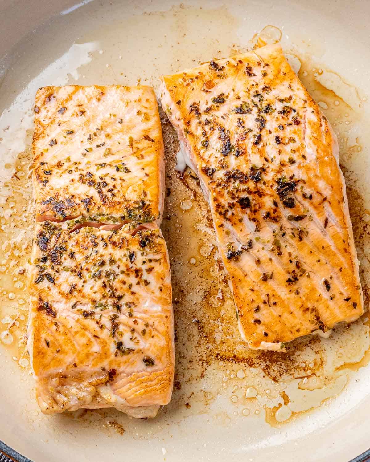 Two salmon filets searing in skillet until golden.