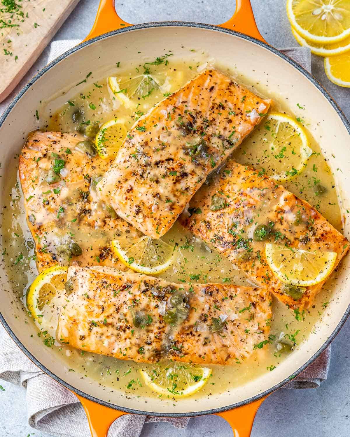 top view salmon piccata on an orange dish