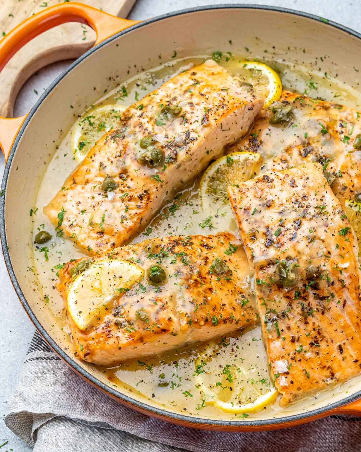 Side of skillet of finished salmon piccata. 