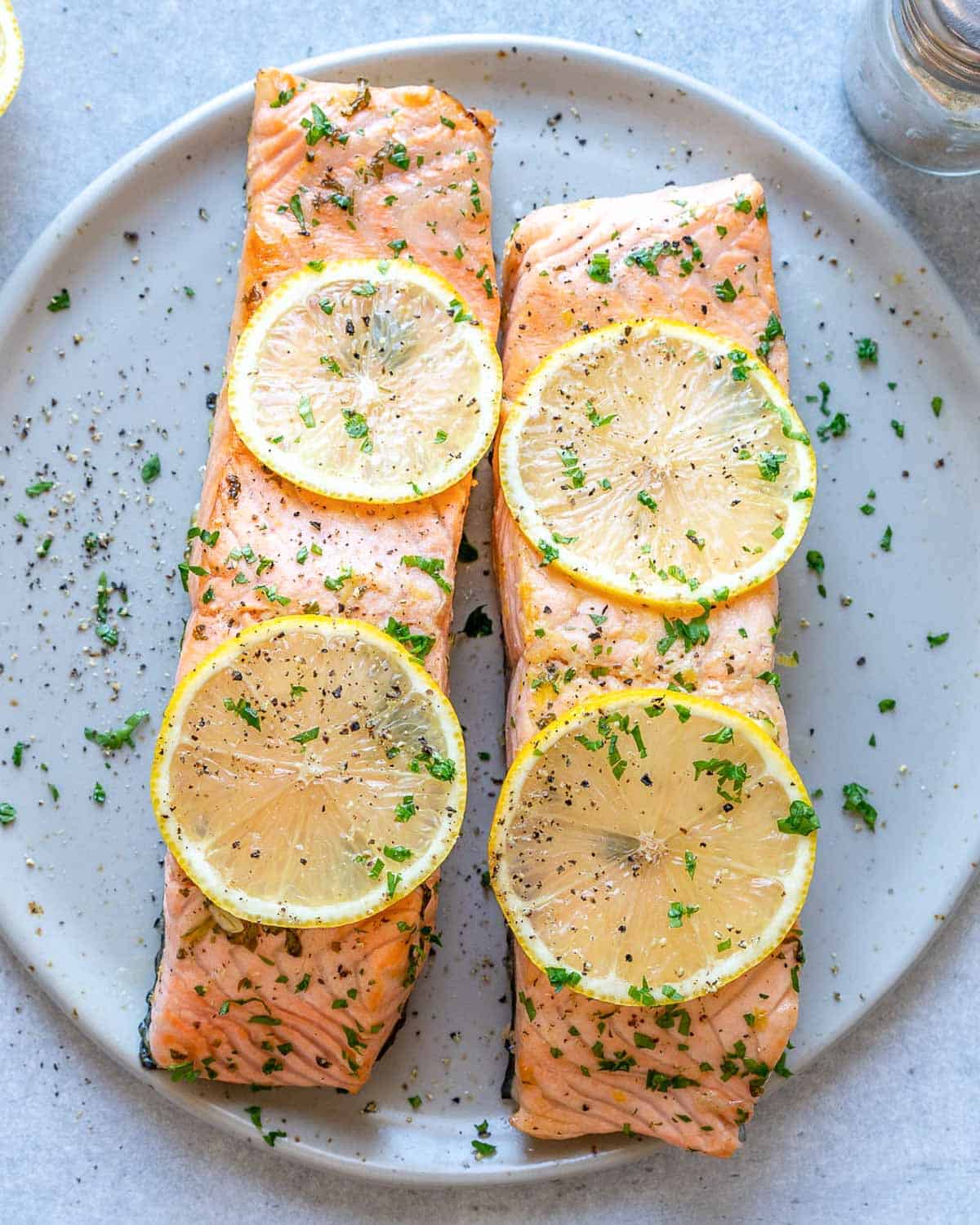 Two baked lemon salmon on a plate.