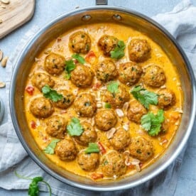 Turkey meatballs in a curry sauce in a stainless steal round pan.