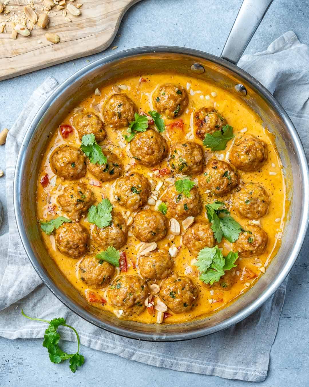 Turkey meatballs in a curry sauce in a stainless steel round pan with cilantro garnish.