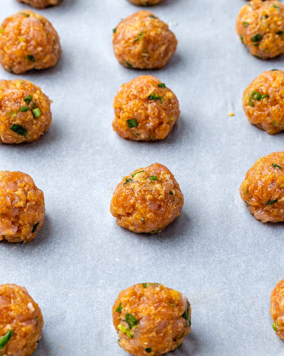 meatballs place on a pan before baking.