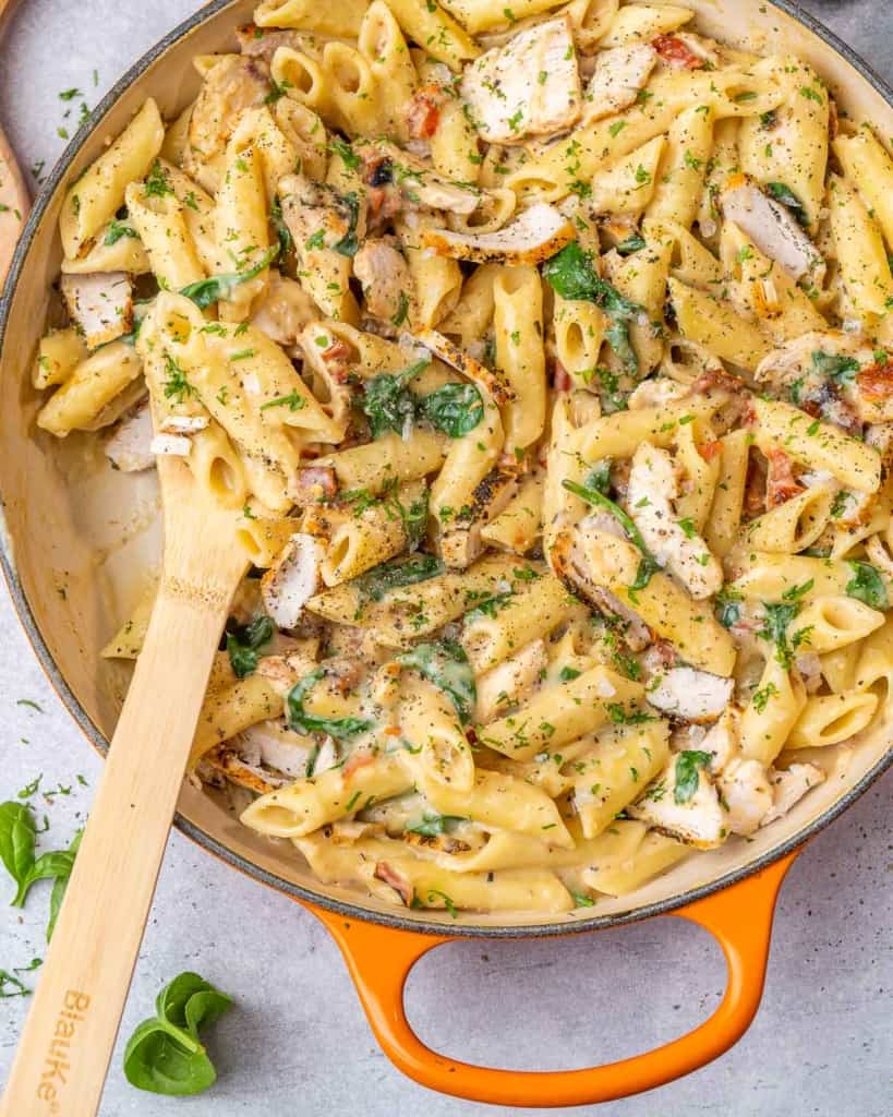 Pasta with chicken and spinach in orange skillet