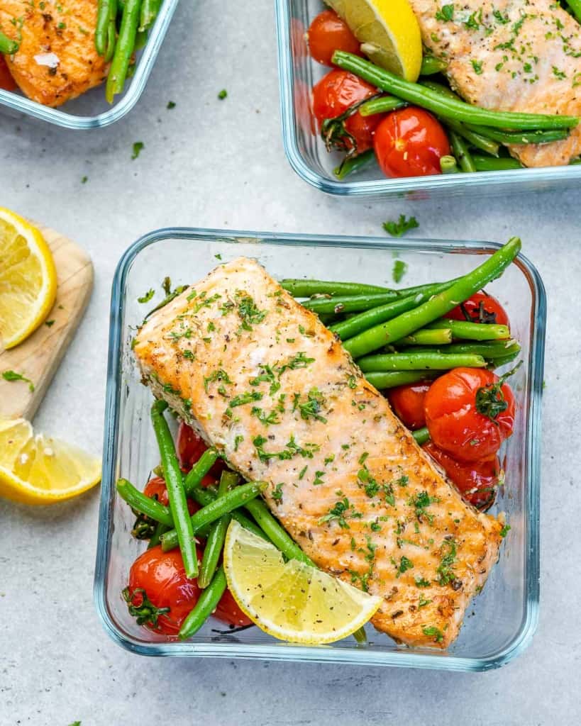 Top view of three salmon meal prep bowls with green beans and tomatoes