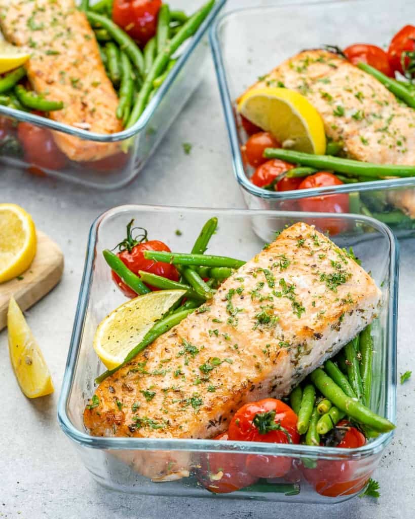 Meal prep lunch box containers with baked salmon fish, rice, green