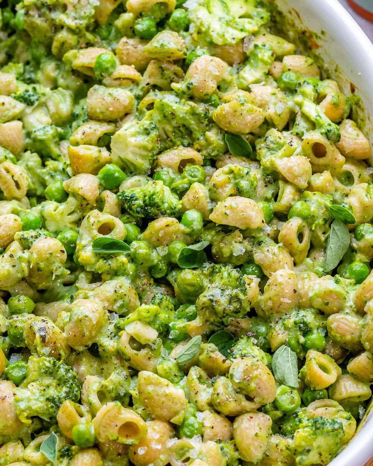 Close view of mac and cheese with broccoli, spinach, and peas.