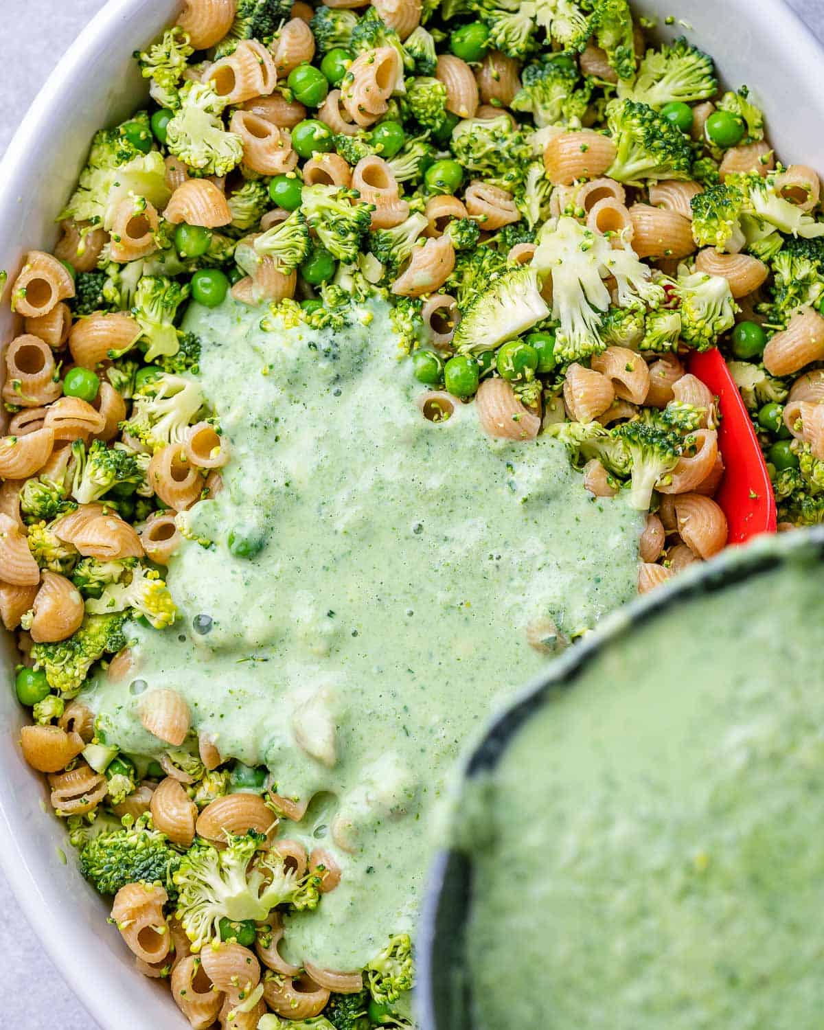 Pouring green cheese sauce into baking dish.