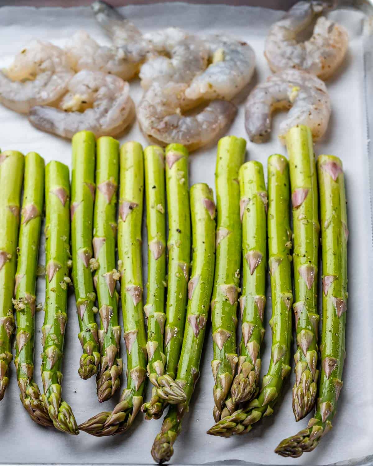 Raw asparagus and shrimp ready to bake on sheet pan.