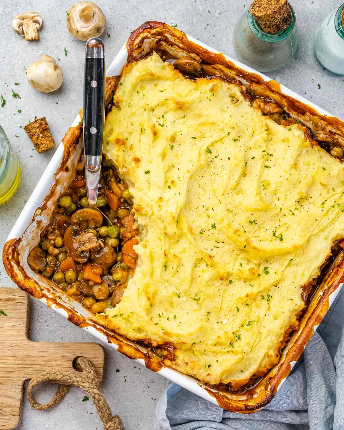 Top view of baked vegetarian shepherd's pie with ingredients on counter. 