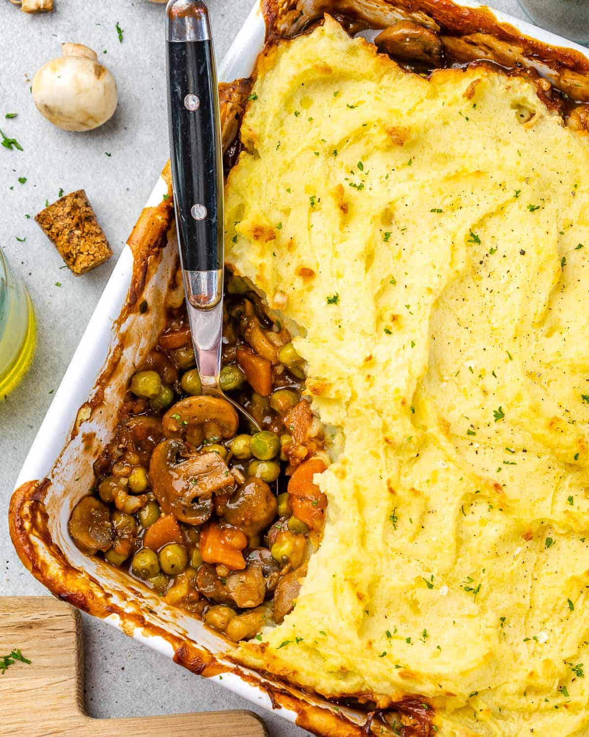 Corner of white baking dish with shepherd's pie scooped out.