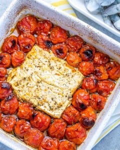 baked tomatoes and block of feta in a white dish