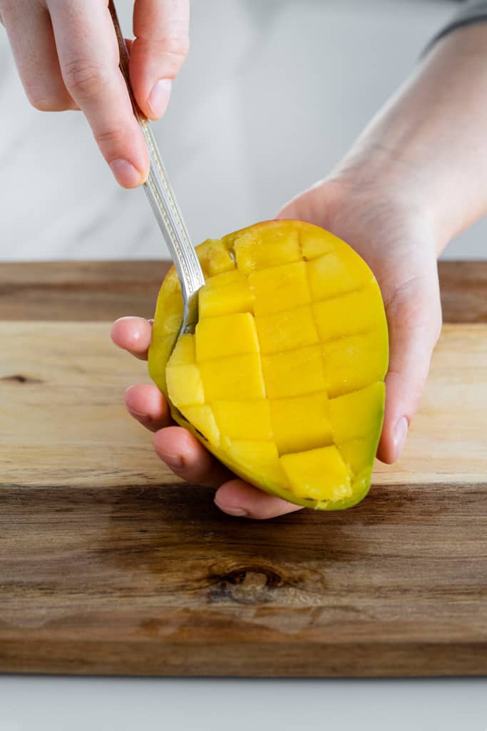spoon scooping mango flesh from mango