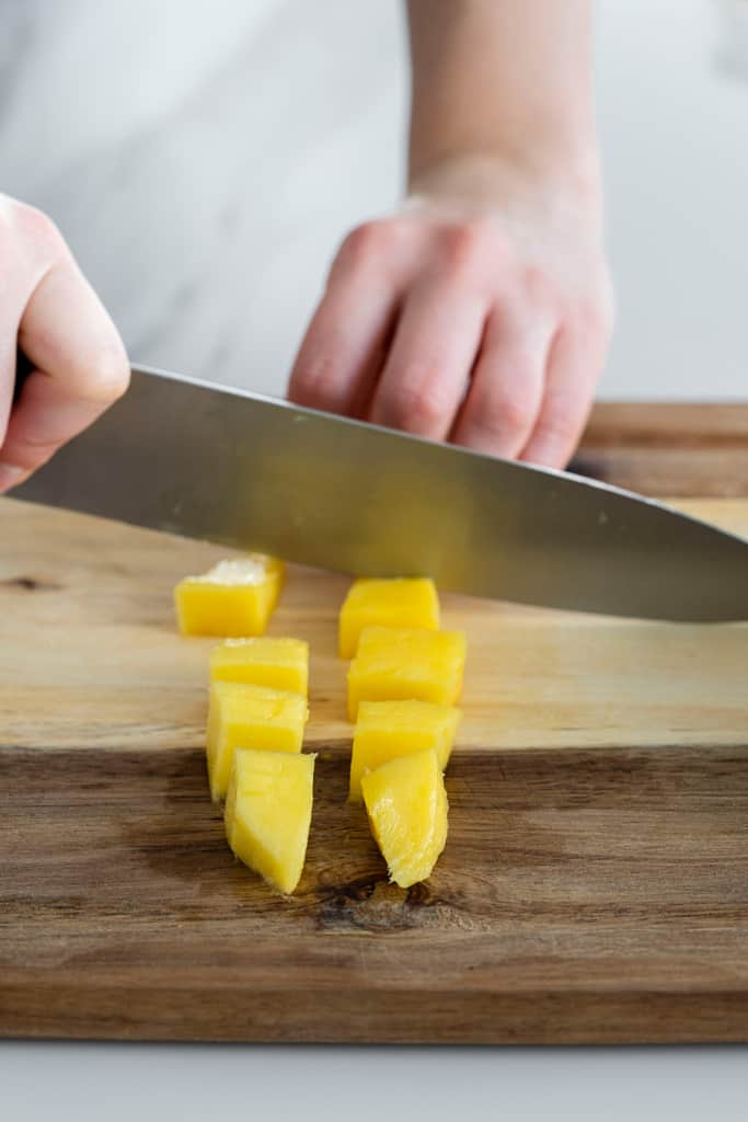mango slice being cut into cubes