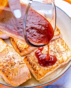 bbq sauce being poured over salmon filets