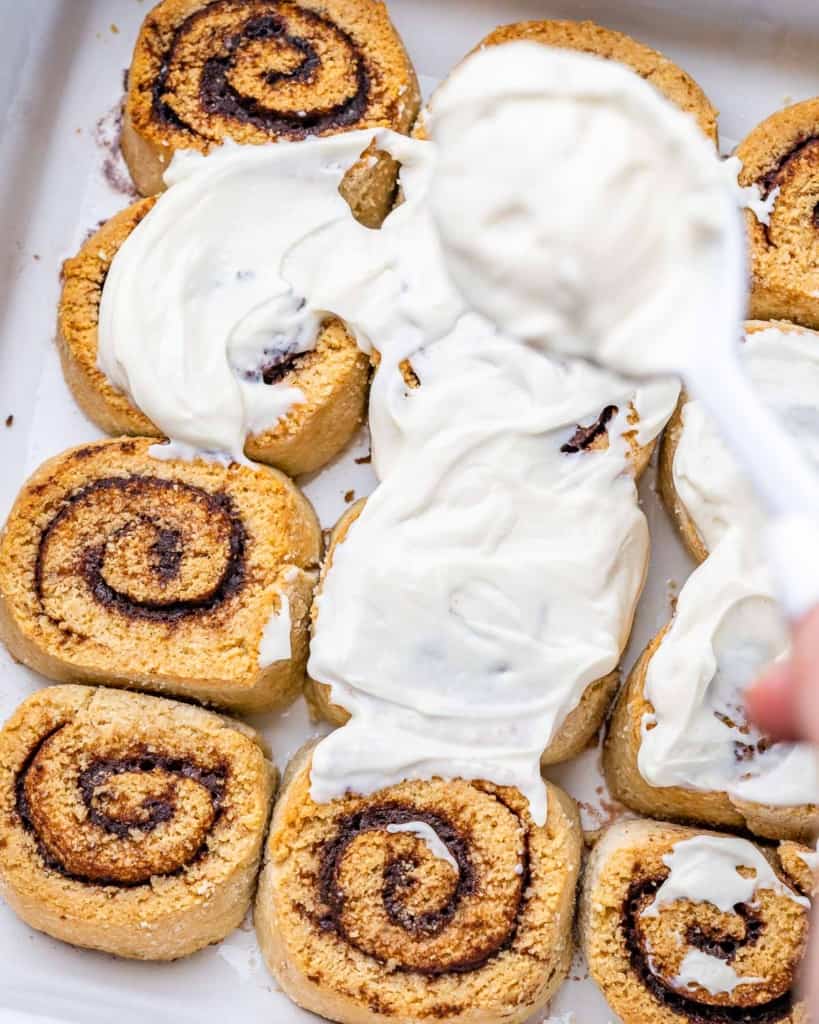 12 keto cinnamon rolls in baking dish with cream cheese glaze