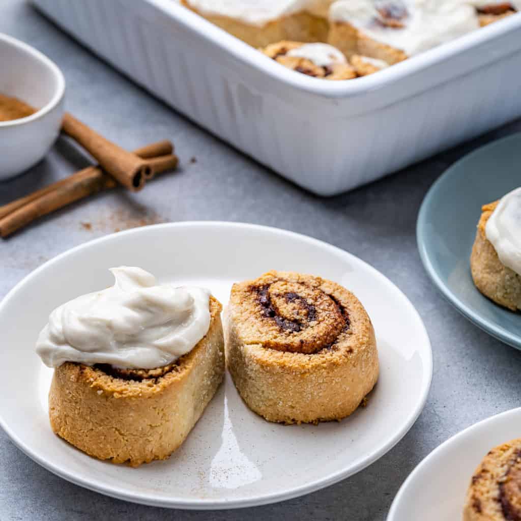 Two cinnamon rolls on white plate with cream cheese glaze