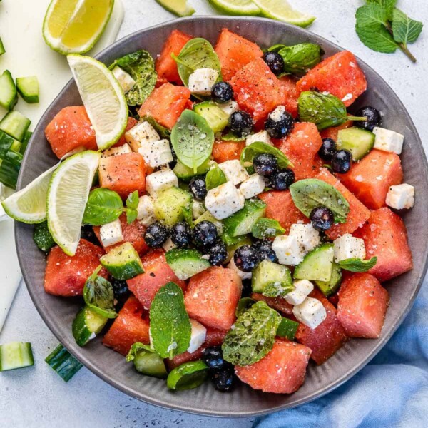 Top view of watermelon feta salad in bowl with lime wedges
