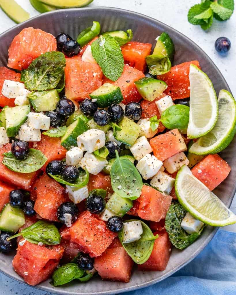 Top view of watermelon feta salad in bowl with lime wedges