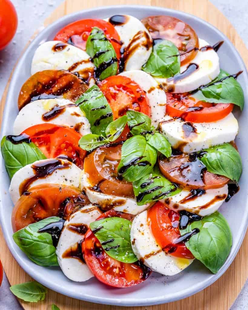 Top view of caprese salad on plate with balsamic drizzle and basil