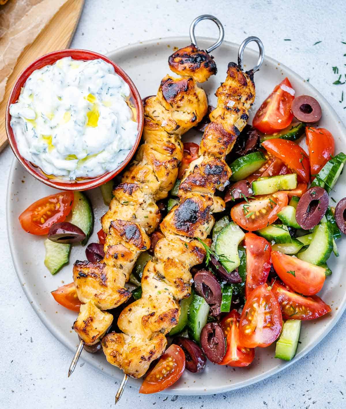 top view of chicken souvlaki with yogurt dip and a side of salad