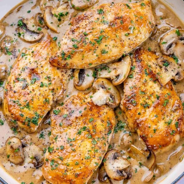 top and close up view of creamy balsamic chicken and mushroom in a yellow skillet