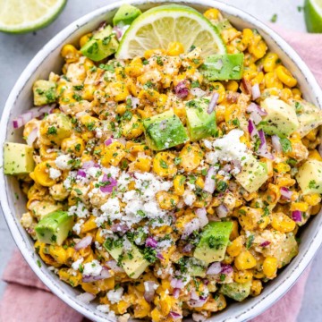 top view street corn salad in a white bowl under a pink napkin