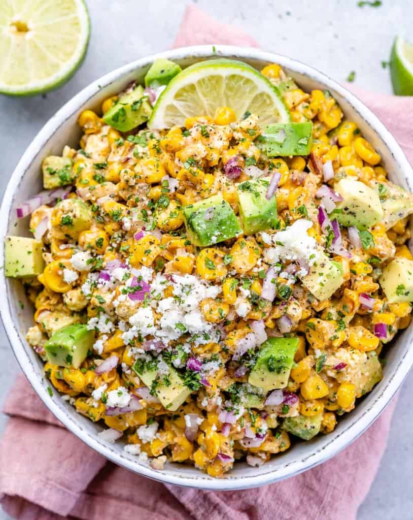 top view street corn salad in a white bowl under a pink napkin