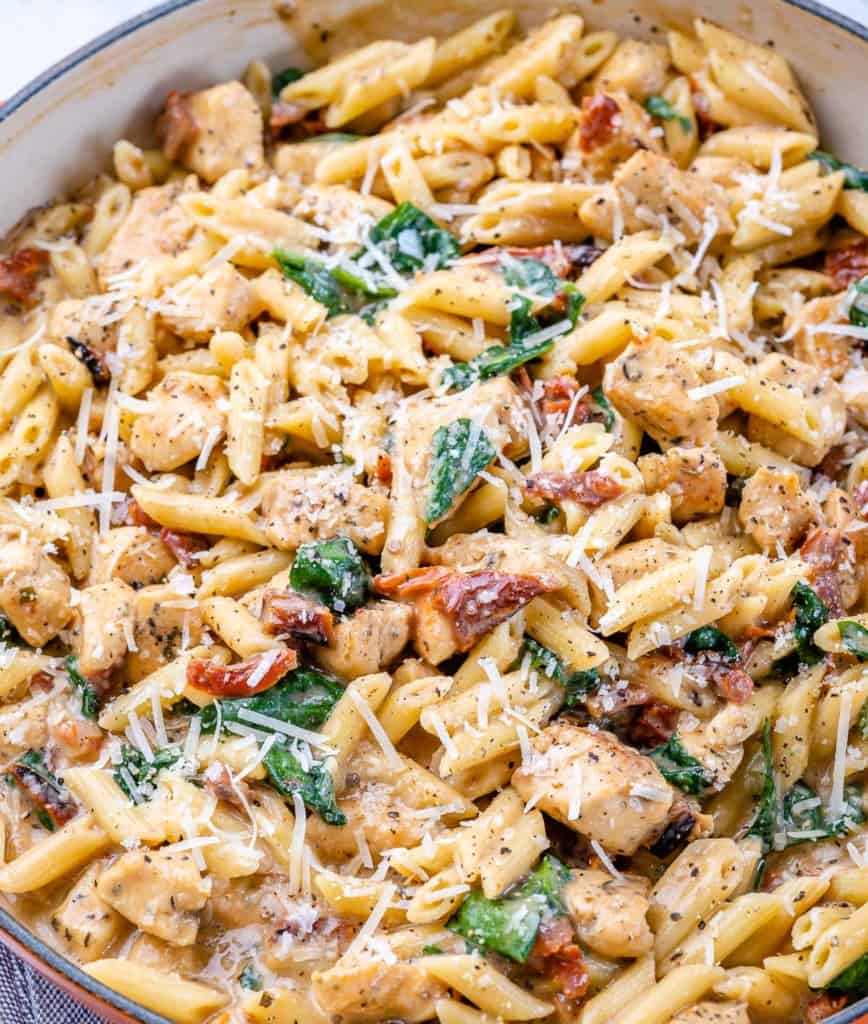 close up chicken pasta in a skillet with parmesan cheese garnish