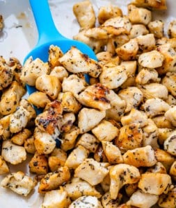 Cooked chicken bites in a pan with a blue spatula in the pan.