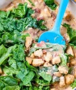 Spinach is added to the creamy chicken sauce in the pan.