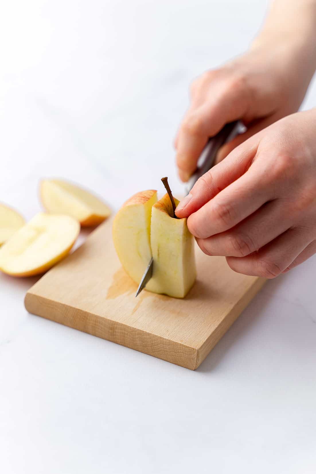 cutting the apple pieces off the core of an apple with a knife 