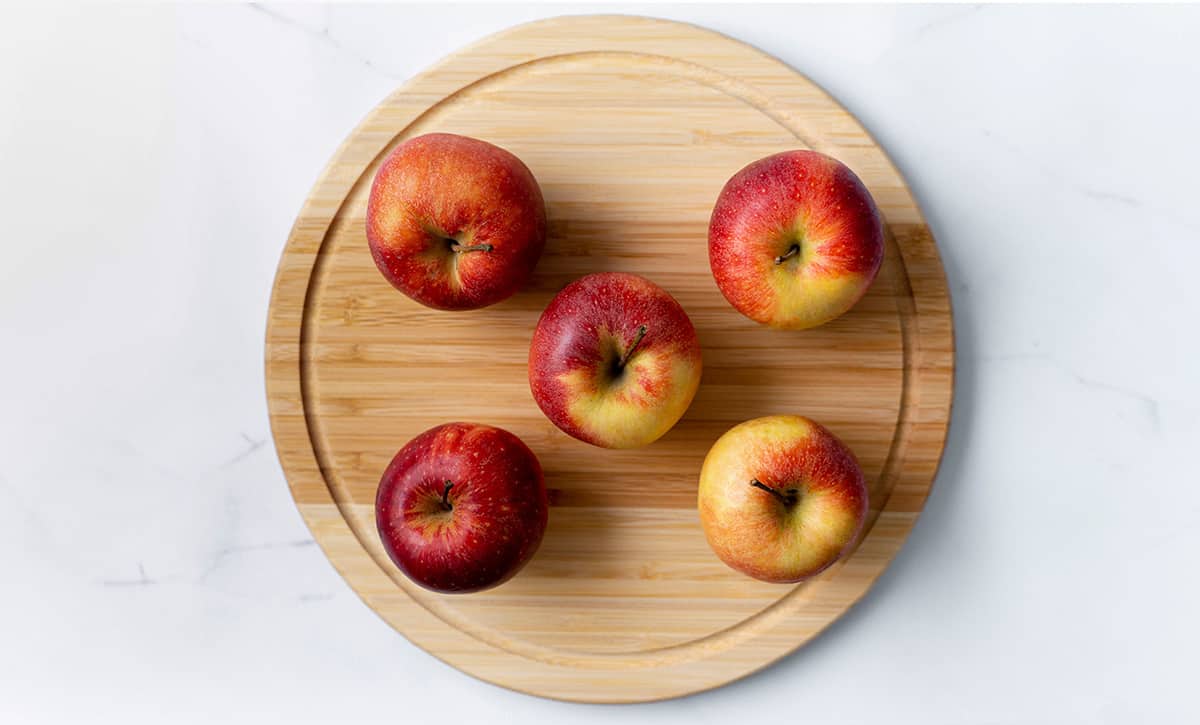 five apples on cutting board
