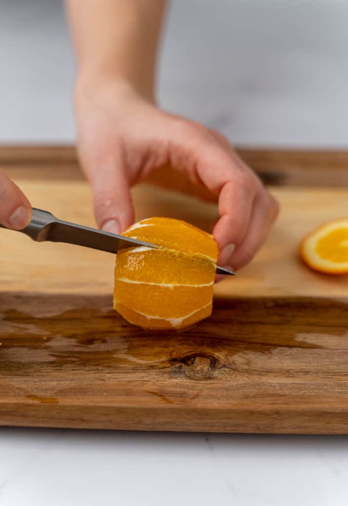 Knife slicing a segment of orange.