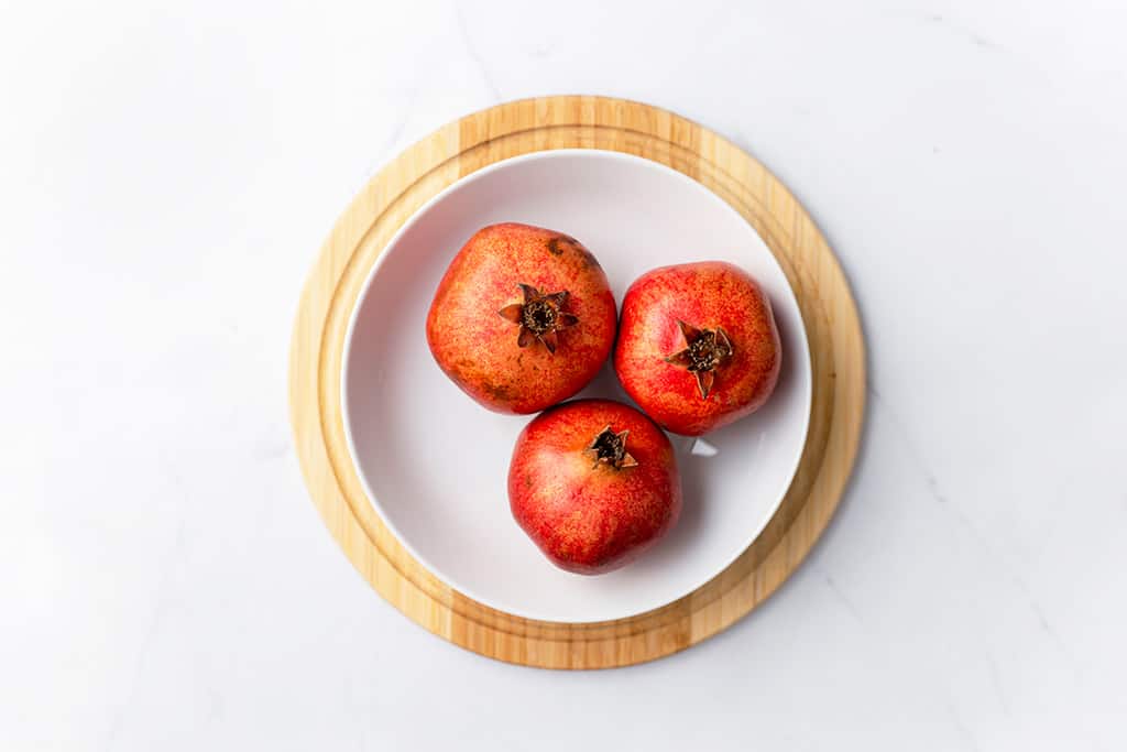 three pomegranates in white bowl 