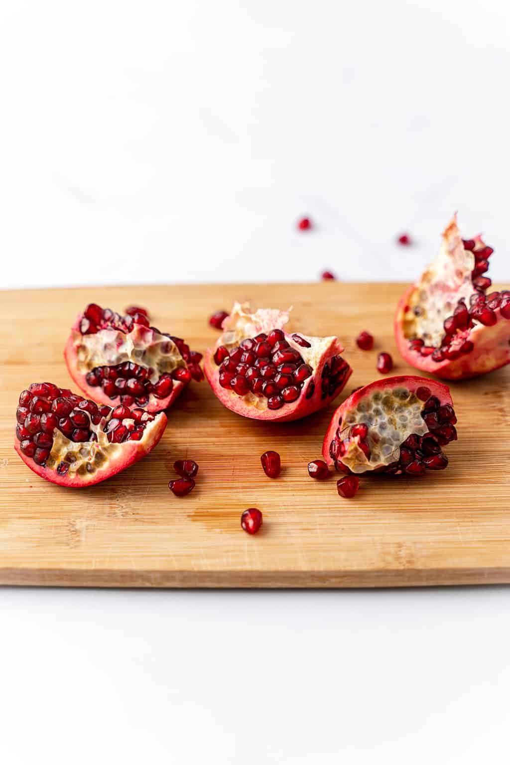 four pomegranate pieces on wooden cutting board