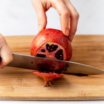 side shot of knife slicing pomegranate