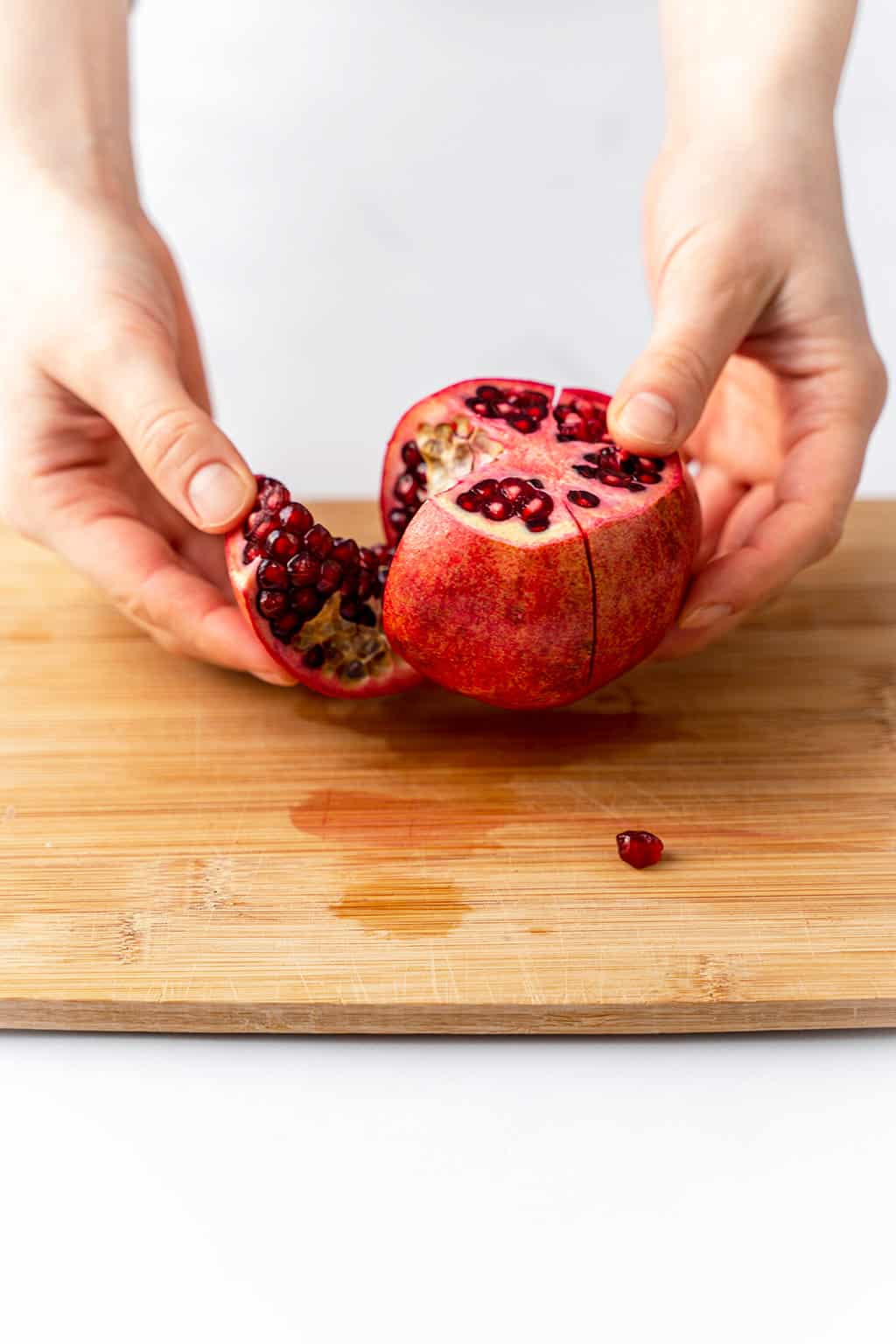 one pomegranate sliced into four segments on cutting board