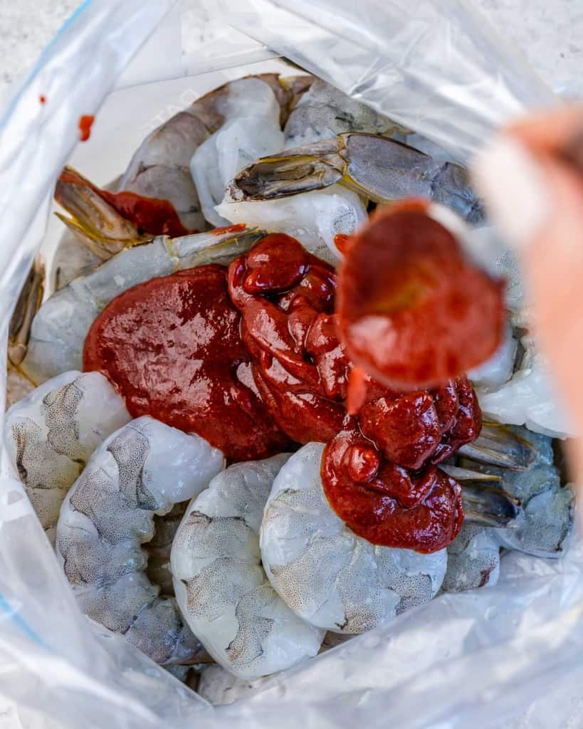 bbq sauce being poured over shrimp in ziplock bag