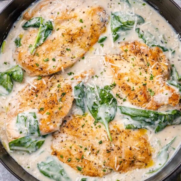 top view of creamy chicken breast with spinach in a black skillet