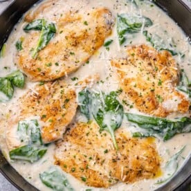 top view of creamy chicken breast with spinach in a black skillet