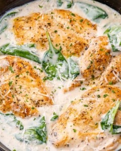 creamy chicken in skillet with spinach and sauce